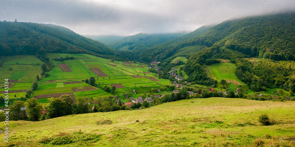 village in the valley of carpathian mountains. rural landscape in early autumn. fields and pastures on the hillside meadows. wonderful nature scenery in the morning