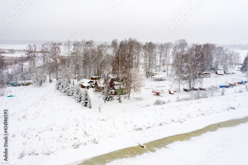 A view from a height on a winter day of a village house and wintering boats on the bank of the canal © Konstantin