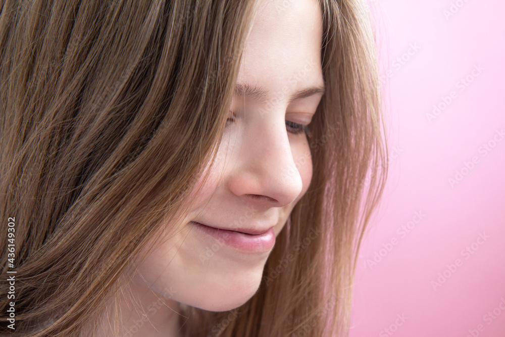 Face of a beautiful smiling teenage girl with long hair on pink background. Happy girl dreams Face of a beautiful smiling teenage girl with long hair on pink background. Happy girl dreams
