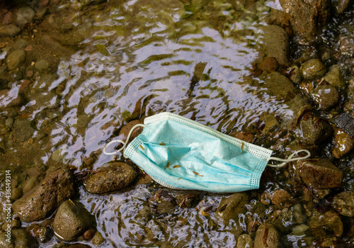 a protective mask thrown into the water of a stream photo