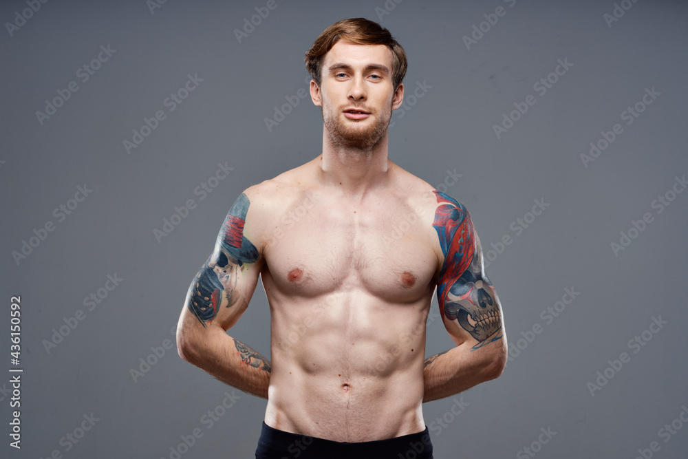 Fototapeta premium sporty man with tattoos on his arms pumped up press macho gray background