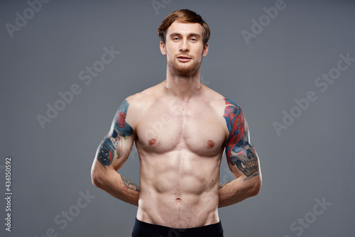 sporty man with tattoos on his arms pumped up press macho gray background