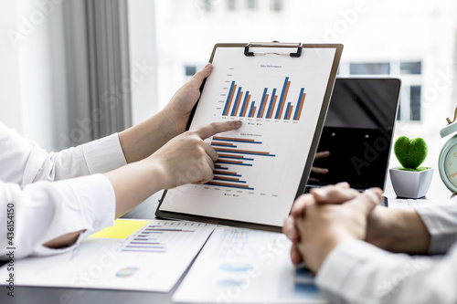 The salesperson is pointing at the monthly sales summary of the sales staff, she is talking to the sales manager to summarize the sales of the sales department to plan to manage the sales to grow. photo