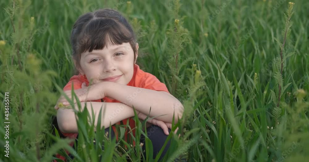 Cute child on a green meadow. Happy little girl sits in the green grass. Cute child on a green meadow. Happy little girl sits in the green grass.
