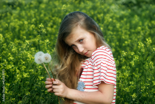 Portrait of a beautiful girl with dandelions in the field