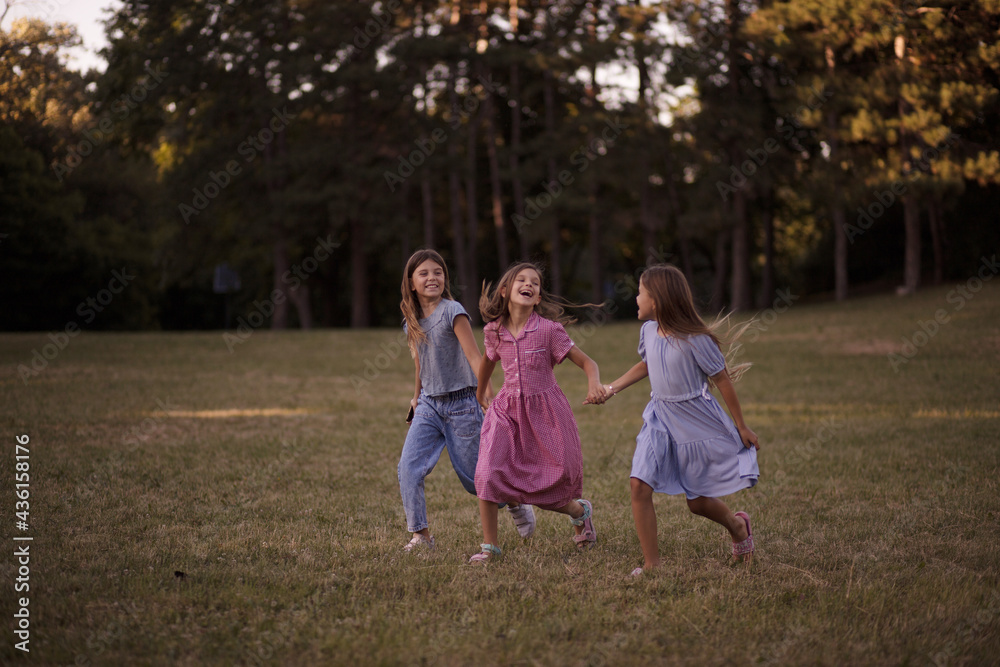 Fototapeta premium Three little girls together in nature. Walking and talking.