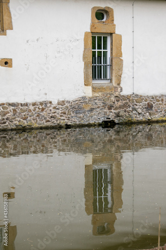 Zwei alte Sprossenfenster mit Spiegelung im Wasser.