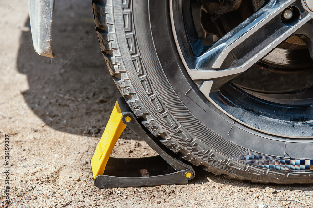 wheel chocks for restricting movement under the wheel of the car. Replacing the wheel on the road by the driver. Replacement of tires on the car by a mechanic after balancing the wheels in close-up. wheel chocks for restricting movement under the wheel of the car. Replacing the wheel on the road by the driver. Replacement of tires on the car by a mechanic after balancing the wheels in close-up.