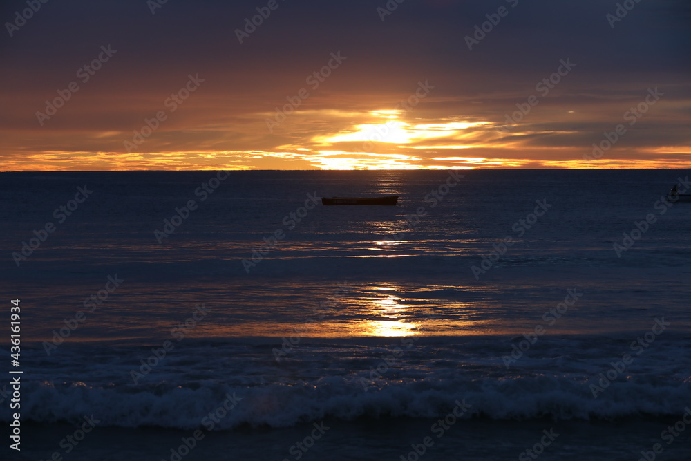 Small fishing boat in the sea at dusk on a beautiful evening in sun glare on the waves at sunset with orange sky on the horizon.Warm seascape.Background image