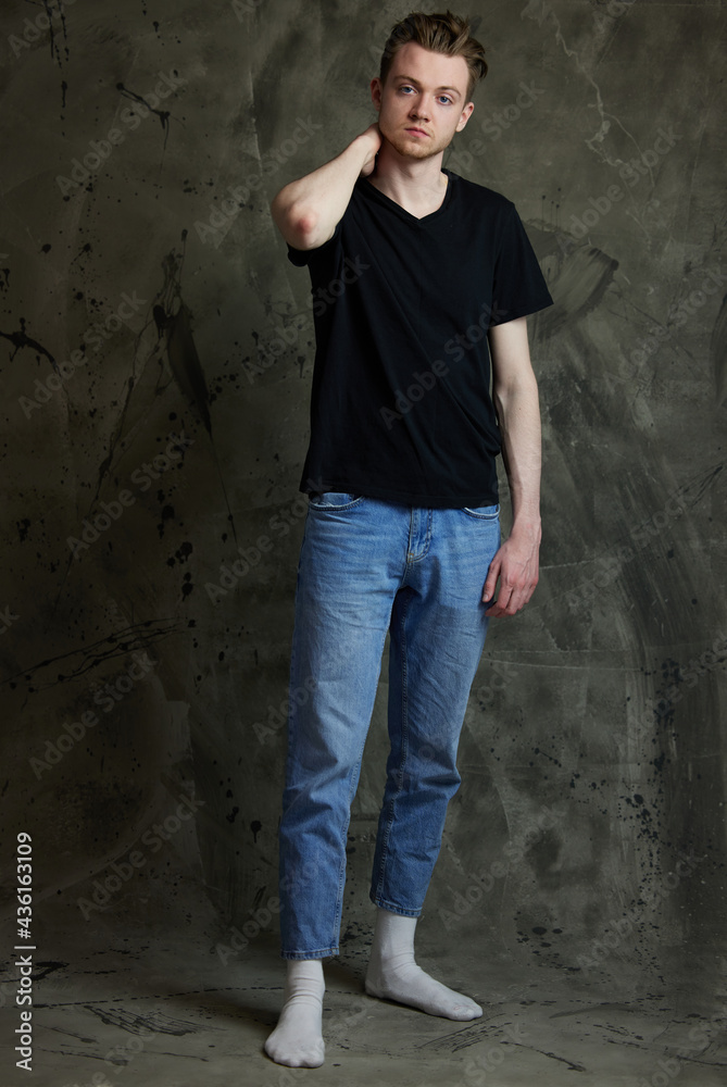 Obraz premium Portrait of a Caucasian handsome guy in full growth in various poses on a gray background. High resolution photos