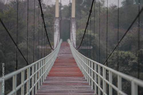 The suspension bridge has a wooden floor with a light green steel handle. Located in Thailand