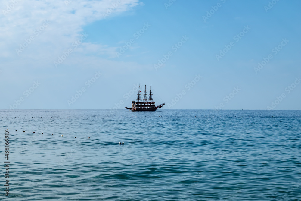 Single pirate schooner among blue water off the coast of Alanya (Turkey). One tourist ship on the horizon. Background with copy space