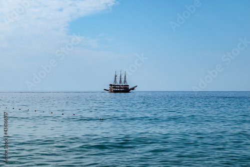 Single pirate schooner among blue water off the coast of Alanya (Turkey). One tourist ship on the horizon. Background with copy space