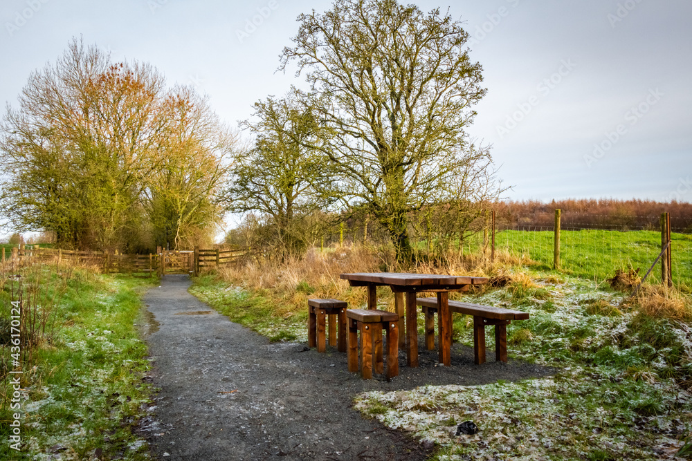 Wooden table and chairs at a seating area on a countryside trail in winter
