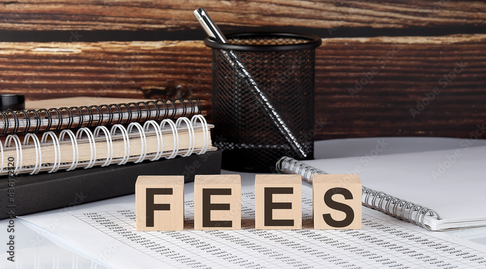 Fototapeta premium FEES text on the wooden block with notebooks on the chart