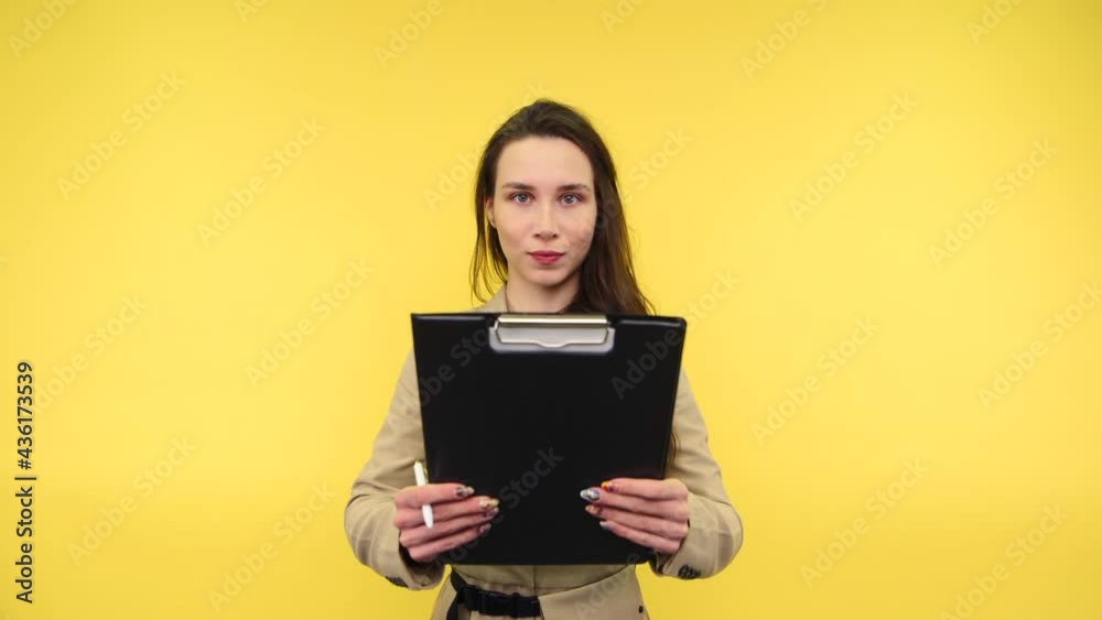 Surprised woman with a tablet with papers in her hands stands on a yellow background, reads with a shocked face and moves her head to the side showing a NO sign. Surprised woman with a tablet with papers in her hands stands on a yellow background, reads with a shocked face and moves her head to the side showing a NO sign.
