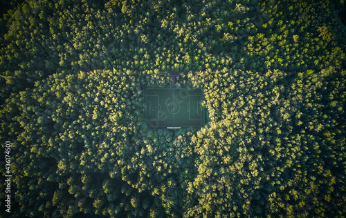 Aerial of soccer pitch in the forest under sunset light