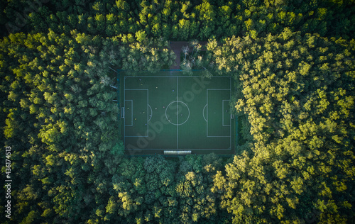 Aerial top down view above the people playing football on a pitch among the forest