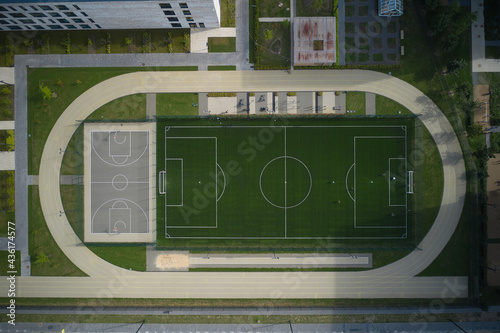 Aerial of schoolyard with basketball court and soccer pitch and running track