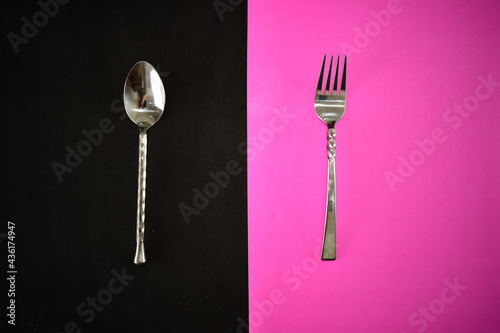silver ware fork and spoon on a bright black and pink napkin