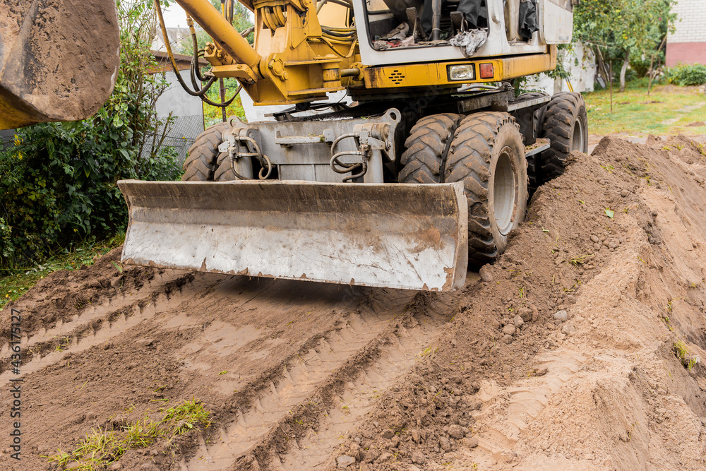 Excavator or bulldozer bucket flattens the ground or road in the industrial zone or construction site Excavator or bulldozer bucket flattens the ground or road in the industrial zone or construction site