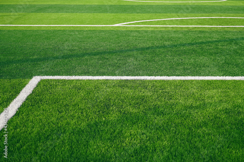 Artificial grass of football field with white stripe, Soccer corner line detail, Green astro turf for texture background, Perspective