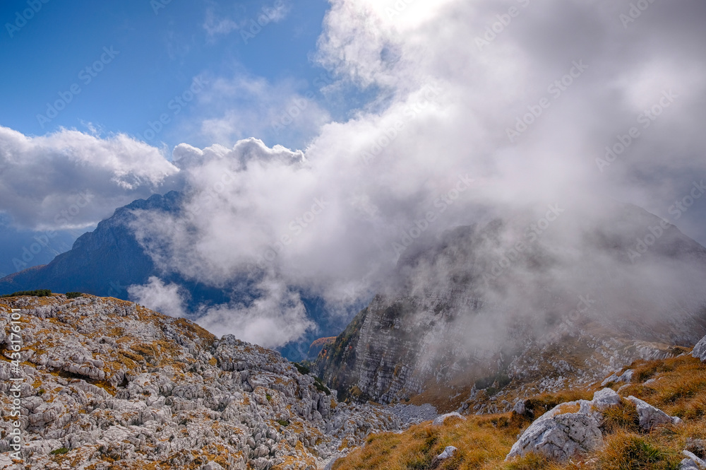 landscape of golden orange and red colors of autumn alps slovenia italy low clouds and first snow bright sunny day