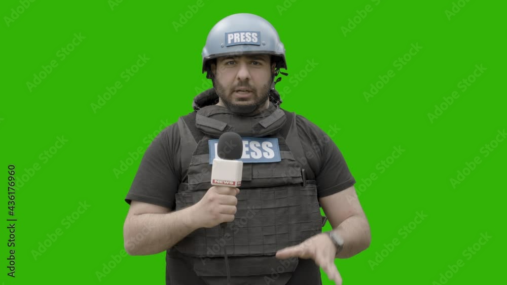 GREEN SCREEN CHROMA KEY War journalist wearing protective helmet and bulletproof vest reporting live in front of the camera