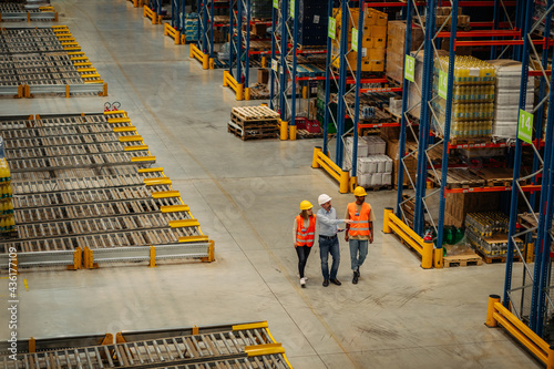 Warehouse employees walking through shelves and talking photo