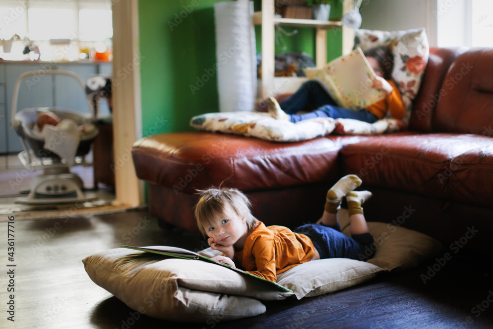 Funny children read books on soft mattresses on the couch and on the floor, real interior, dark style