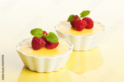 Photo Vanilla custard with fresh raspberries on pastel yellow background