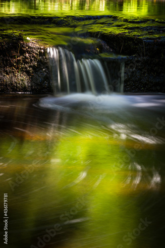 Cascading waterfall cascades in Estonia in green light at summertime