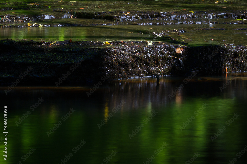 Cascading waterfall cascades in Estonia in green light at summertime