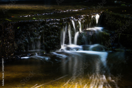Cascading waterfall cascades in Estonia in green light at summertime