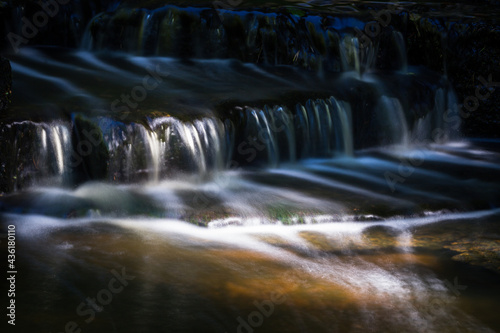 Cascading waterfall cascades in Estonia in green light at summertime