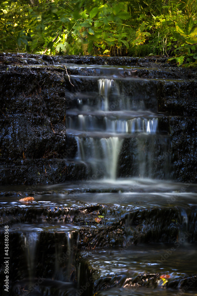 Obraz premium Cascading waterfall cascades in Estonia in green light at summertime