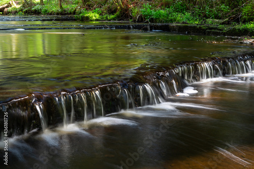 Cascading waterfall cascades in Estonia in green light at summertime