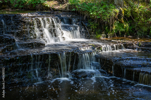 Cascading waterfall cascades in Estonia in green light at summertime