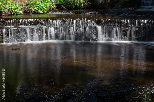 Cascading waterfall cascades in Estonia in green light at summertime