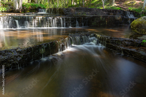 Cascading waterfall cascades in Estonia in green light at summertime