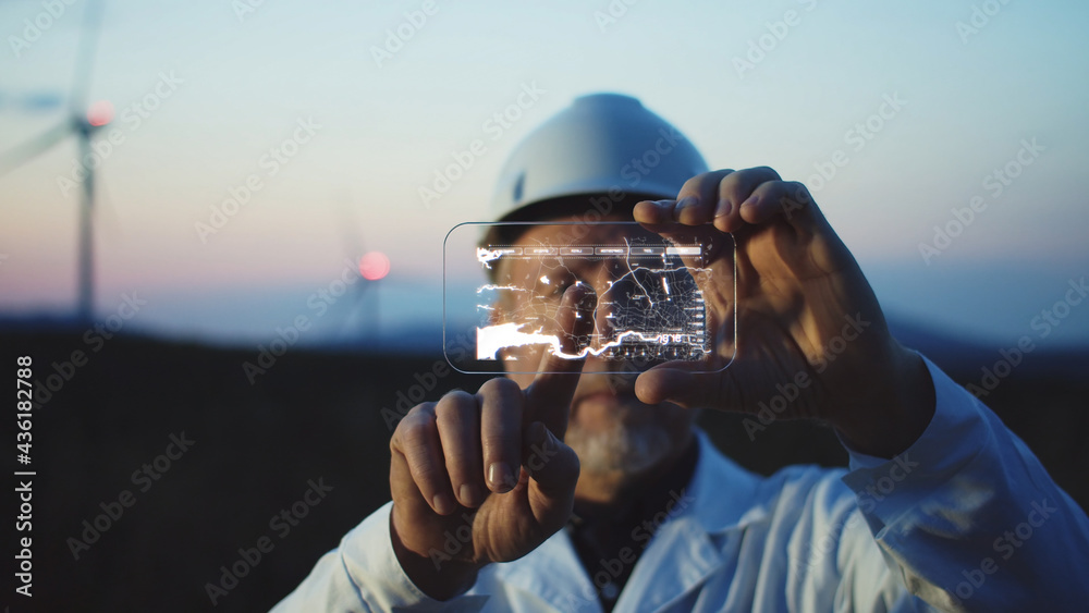 Adult man scientist using high tech smart phone to diagnose online the workflow on modern windmill farm. Beautiful sunset sky on background. The newest technology trend of communication. - obrazy, fototapety, plakaty 