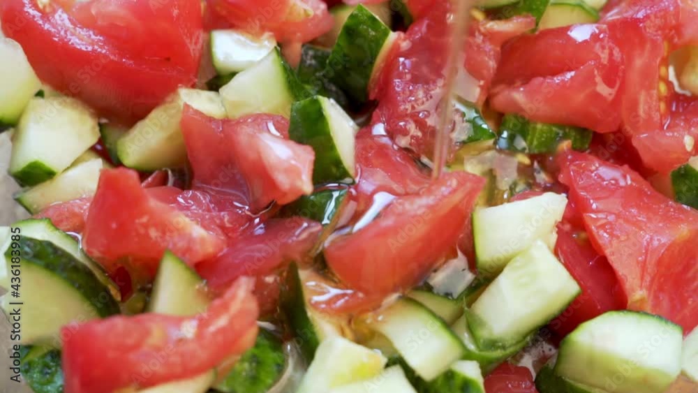 Pouring Olive Oil on a Healthy Salad of Chopped Fresh Vegetables, Cucumbers and Tomatoes, Macro, Close-up. Healthy Vegetarian Food and Diet. Pouring Olive Oil on a Healthy Salad of Chopped Fresh Vegetables, Cucumbers and Tomatoes, Macro, Close-up. Healthy Vegetarian Food and Diet.