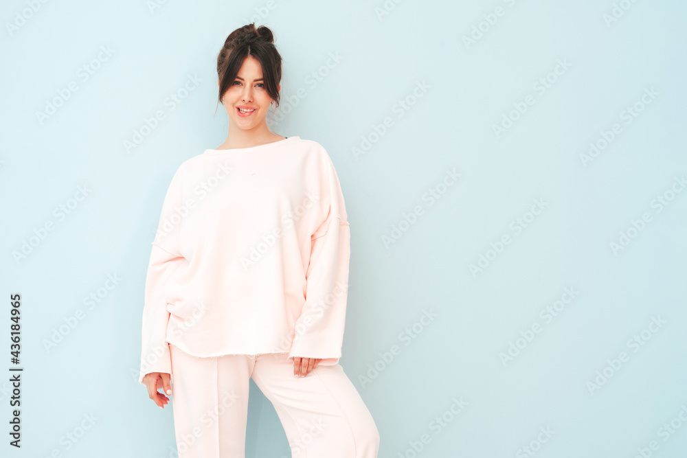 Portrait of young beautiful smiling female in trendy summer pink clothes. Sexy carefree woman posing near light blue wall in studio. Positive model having fun indoors. Biting her finger Portrait of young beautiful smiling female in trendy summer pink clothes. Sexy carefree woman posing near light blue wall in studio. Positive model having fun indoors. Biting her finger