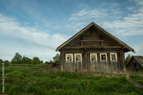 An old, abandoned log house. Deserted village in Russia. A lonely hut without people. Rotten wall construction. Hut against the background of the blue sky. Karelia. Russia. Day. © Viktor