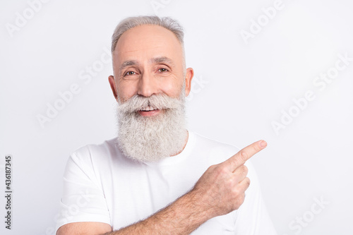 Photo of cheerful happy old grandfather smile point finger empty space recommend sale isolated on grey color background