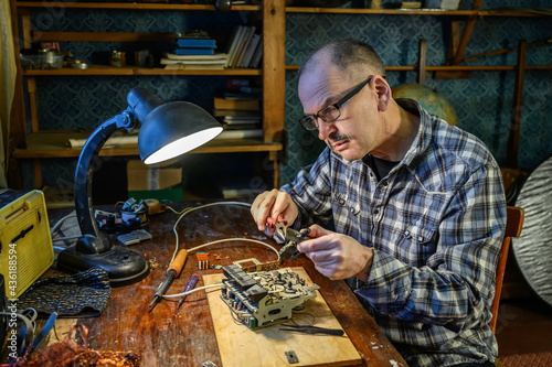 Adult male repairing an old radio receiver at home