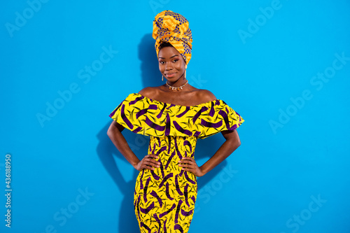 Photo of charming positive dark skin lady put arms on waist look camera isolated on blue color background photo