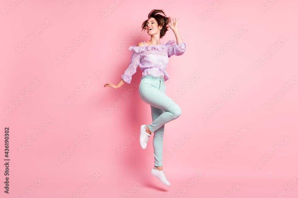 Full size photo of young attractive beautiful happy excited smiling girl with flying hair jumping isolated on pink color background