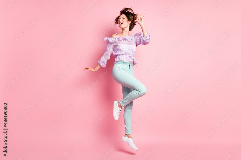 Full size photo of young attractive beautiful happy excited smiling girl with flying hair jumping isolated on pink color background Full size photo of young attractive beautiful happy excited smiling girl with flying hair jumping isolated on pink color background