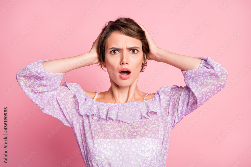 Photo portrait of panicking woman holding head with two hands isolated on pastel pink colored background Photo portrait of panicking woman holding head with two hands isolated on pastel pink colored background